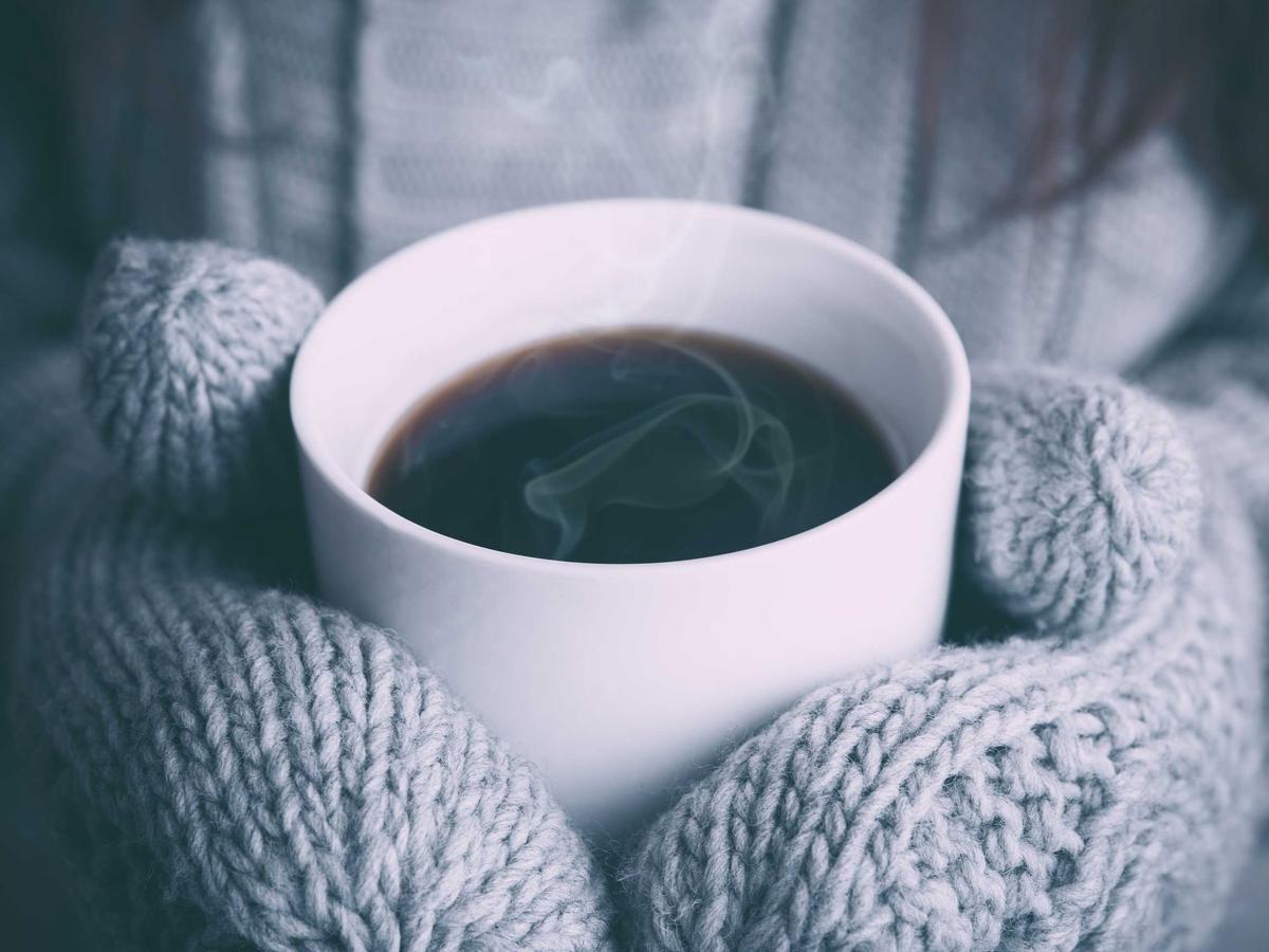 Wool mittens around a cup of coffee