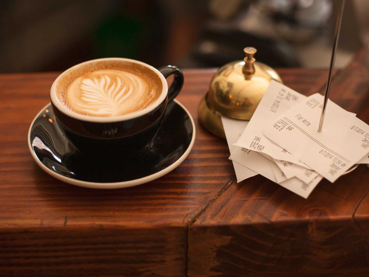 A cappuccino beside a brass bell