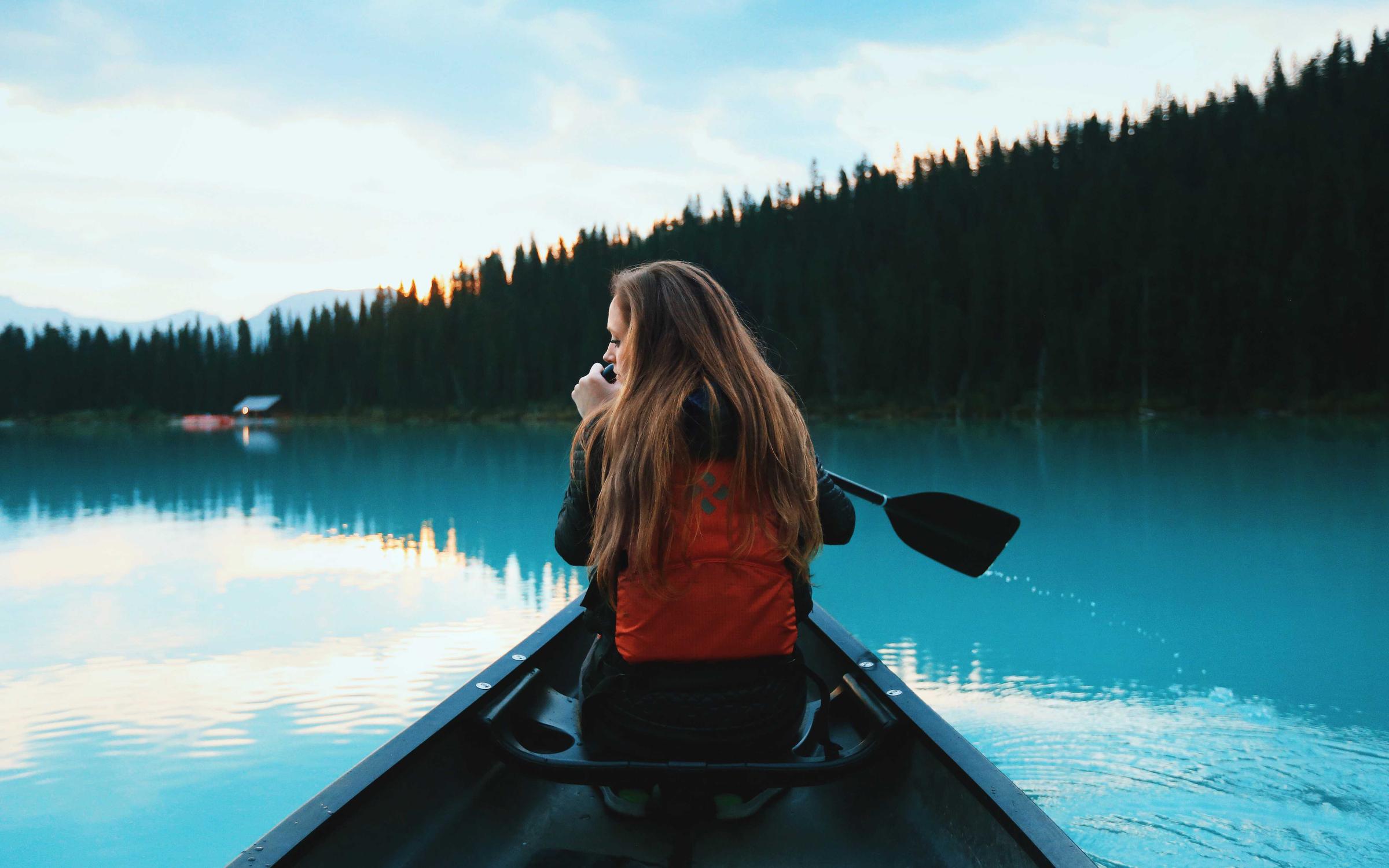 A guest paddling a canoe on a bright summer lake